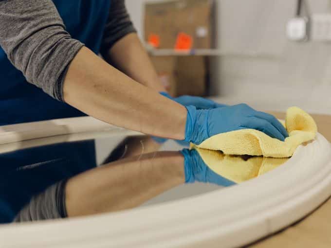 Gloved hands drying and cleaning a water-affected furniture surface